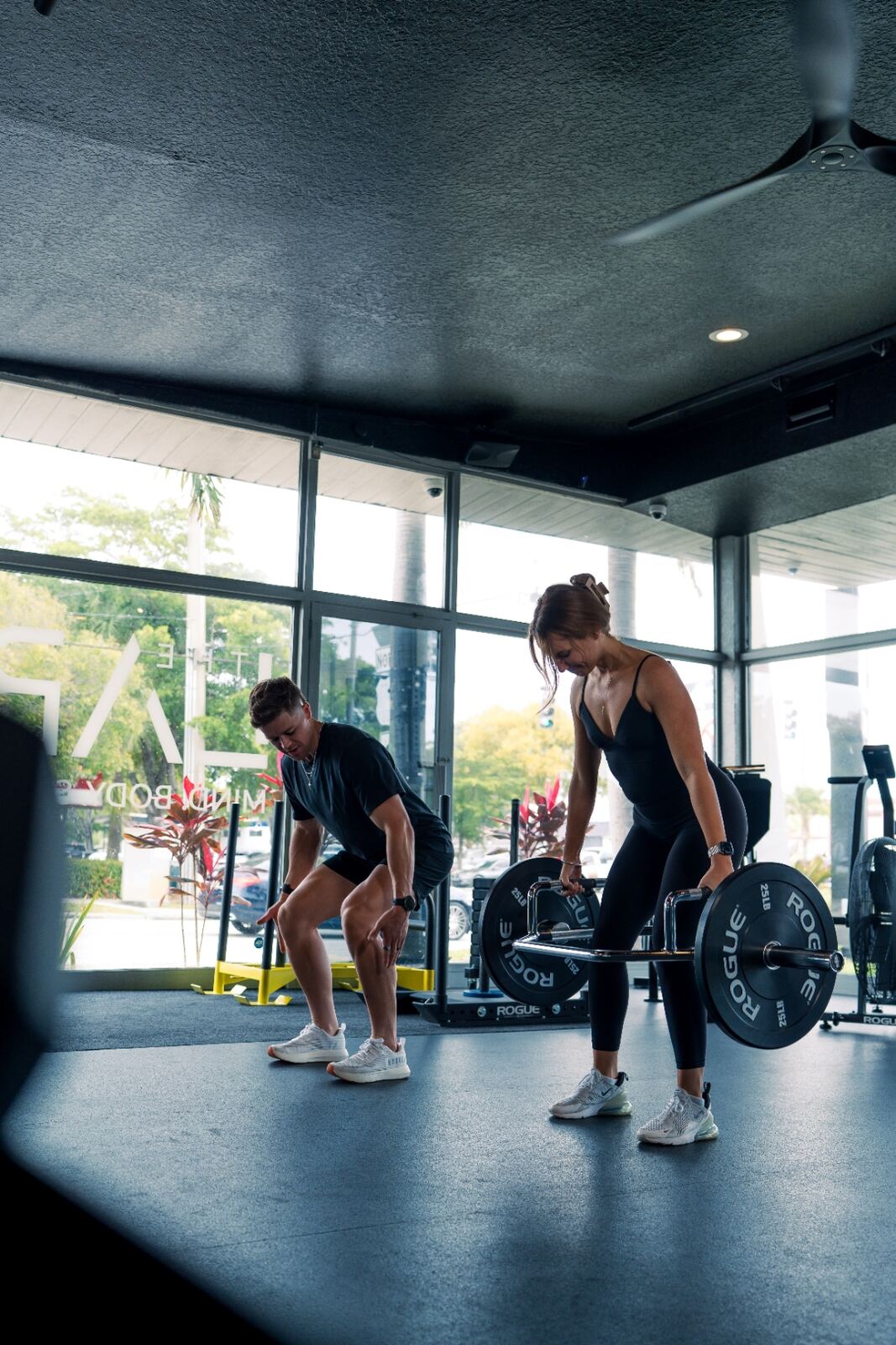 Dylan coaching a client through a deadlift by the studio windows